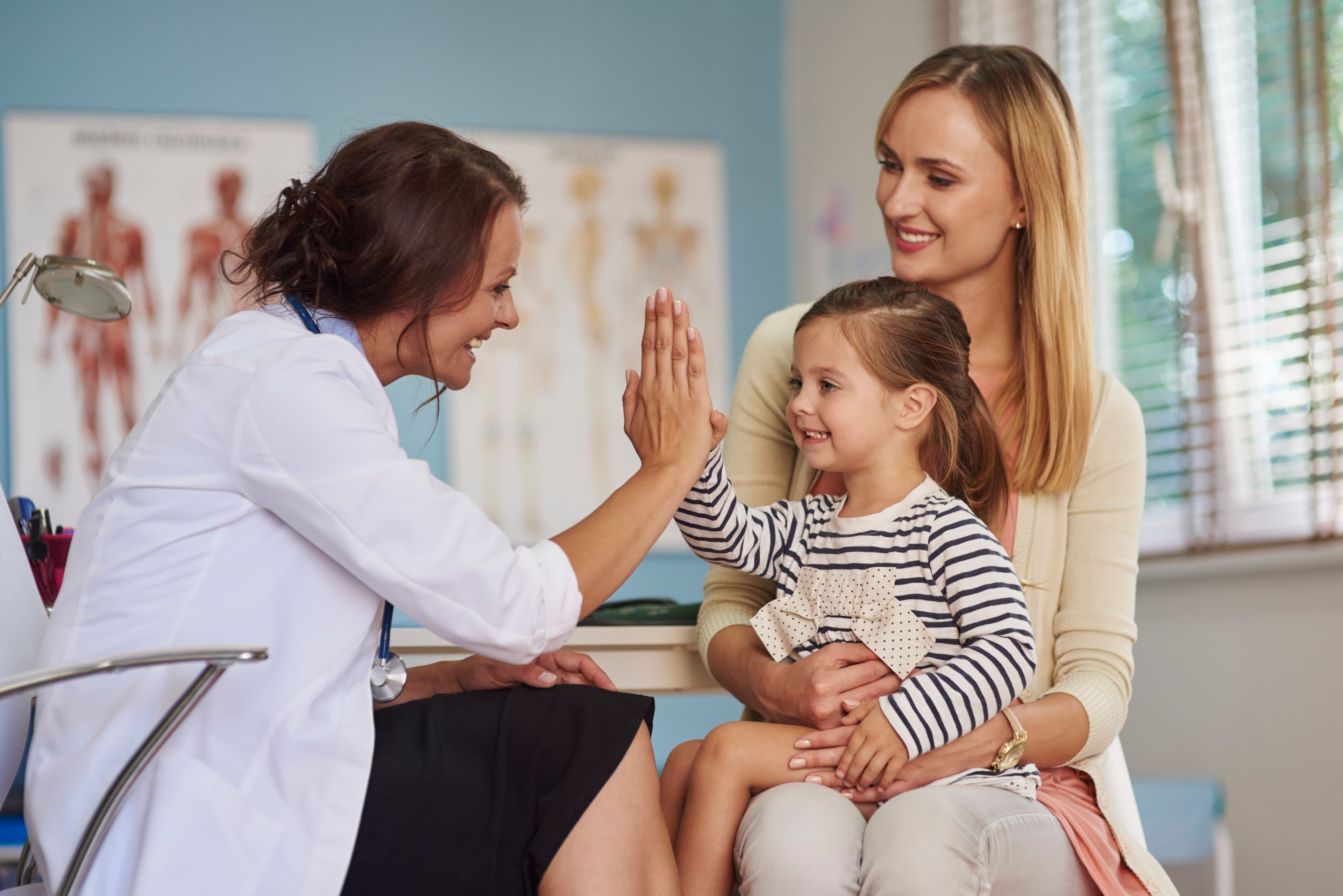 Doctor giving high five to young patient with mother